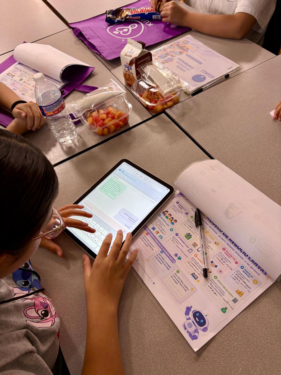 Participante usando una tablet y una guia de trabajo Kuali